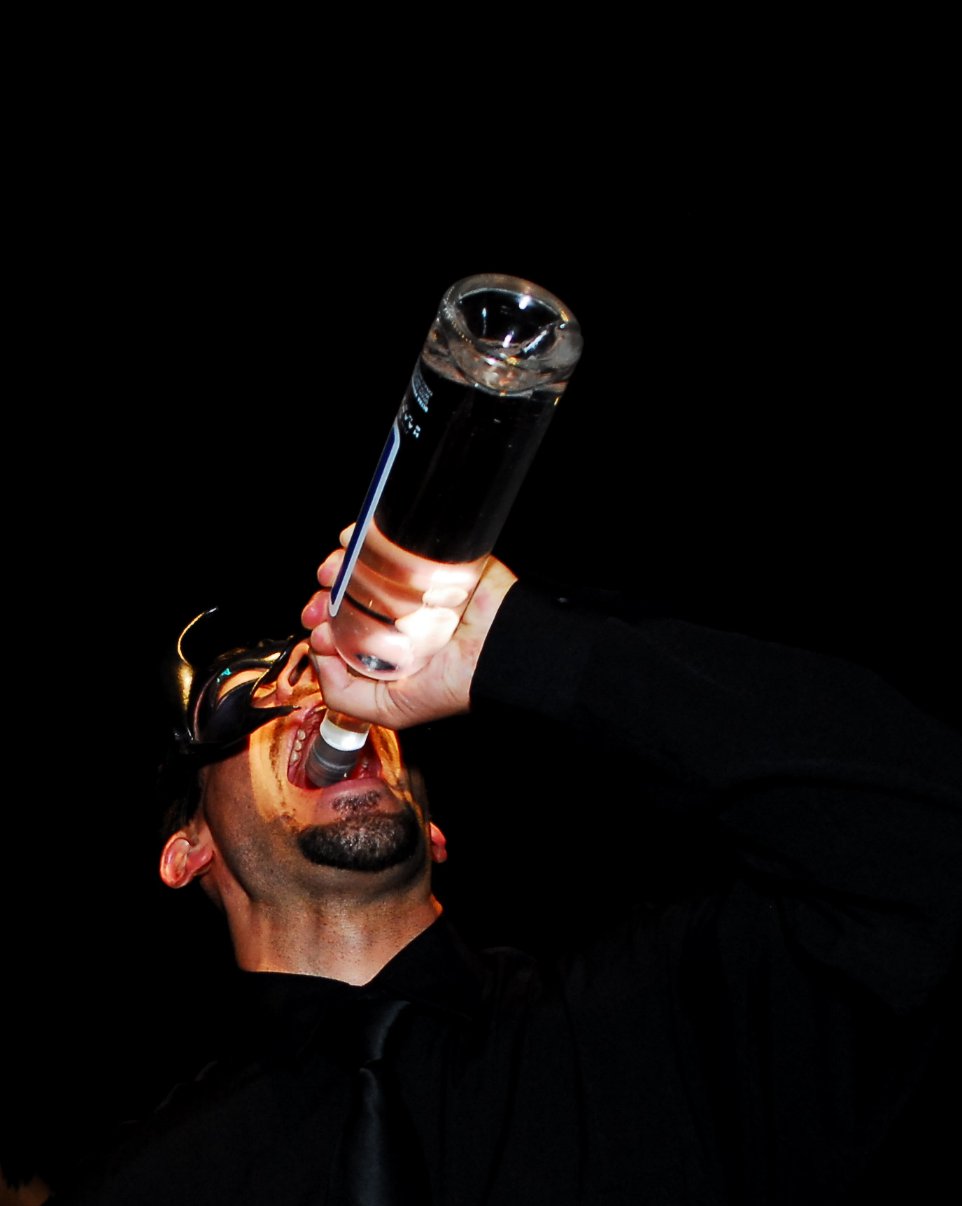 a man with dark hair holds a glass up to his head