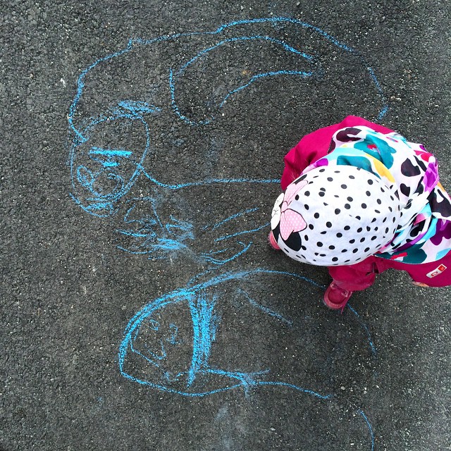 a small child on the ground drawing on a pavement