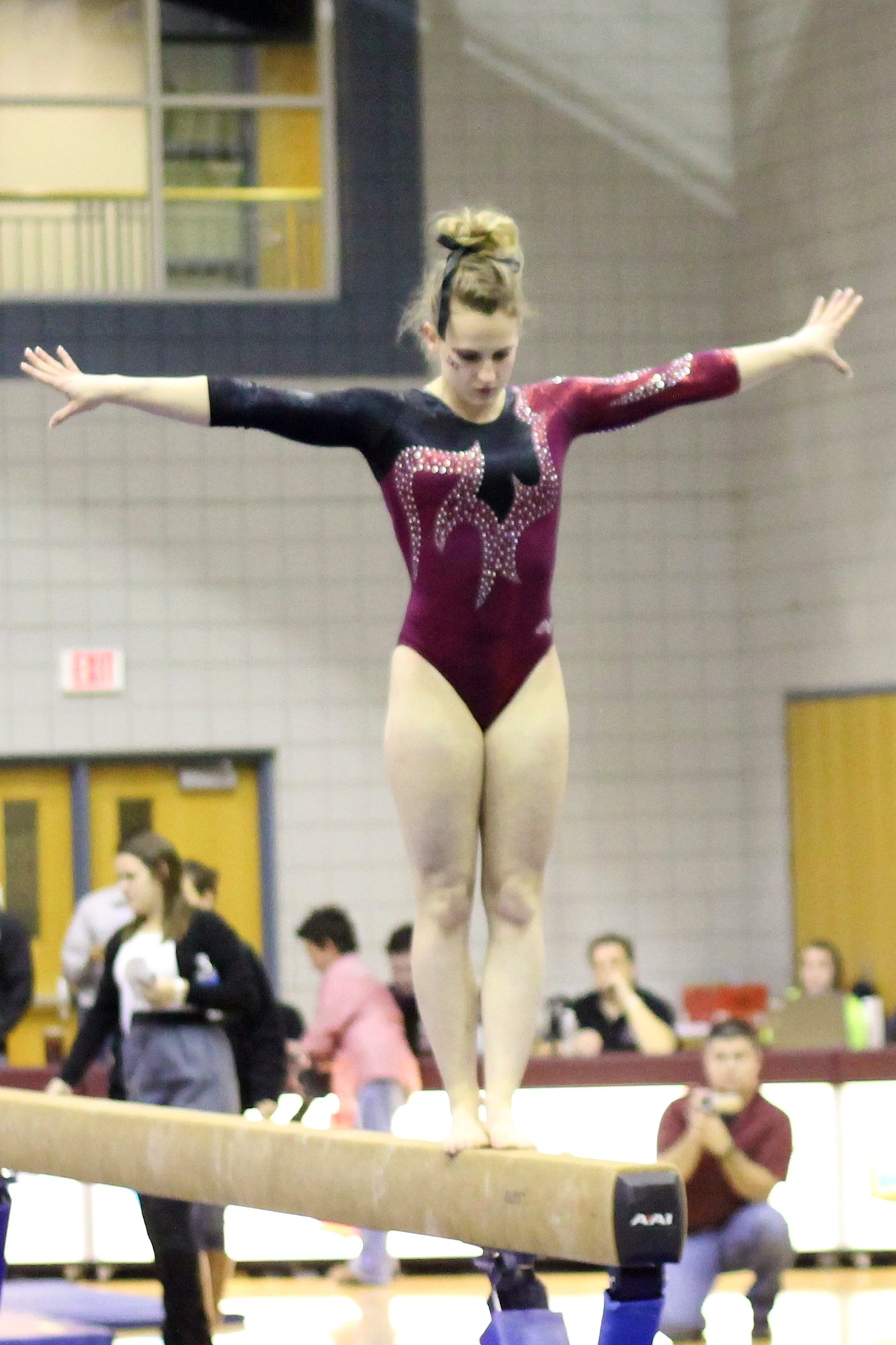 a girl on an exercise balance beam, holding out her arms