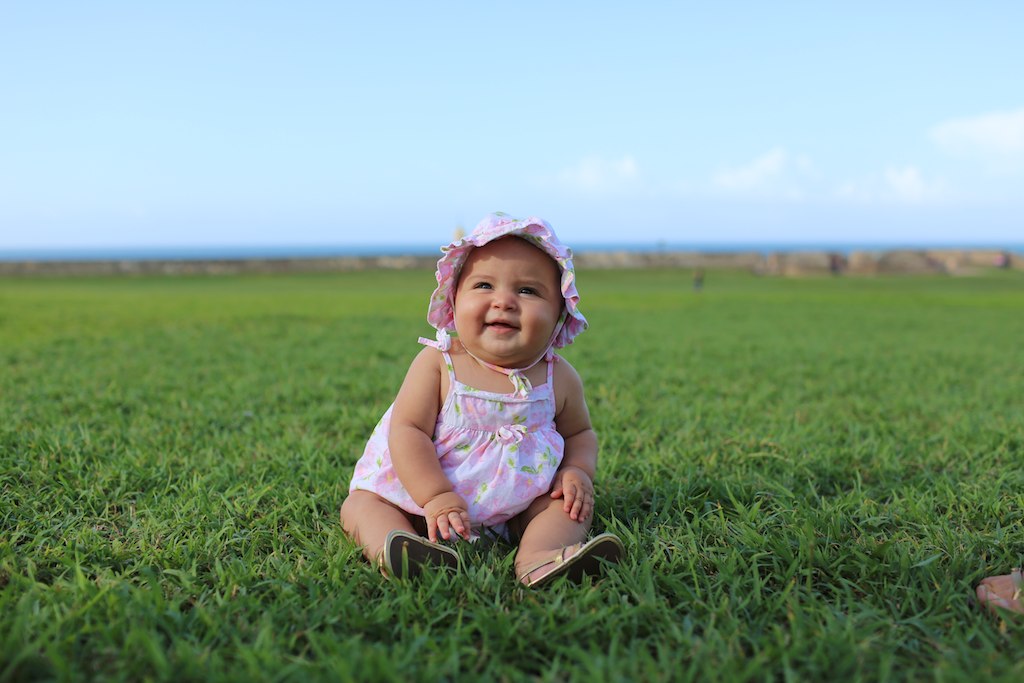 a little girl sitting in the grass smiling