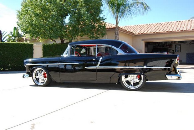 a classic black car parked in a driveway next to a house