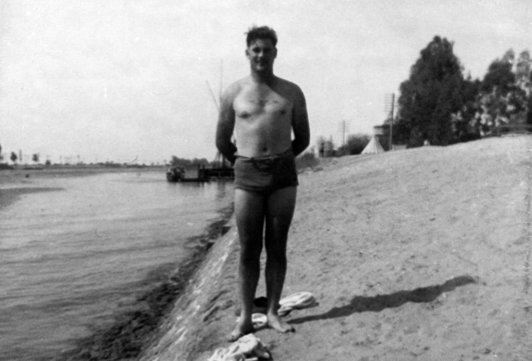a man in underwear is standing on the beach near water