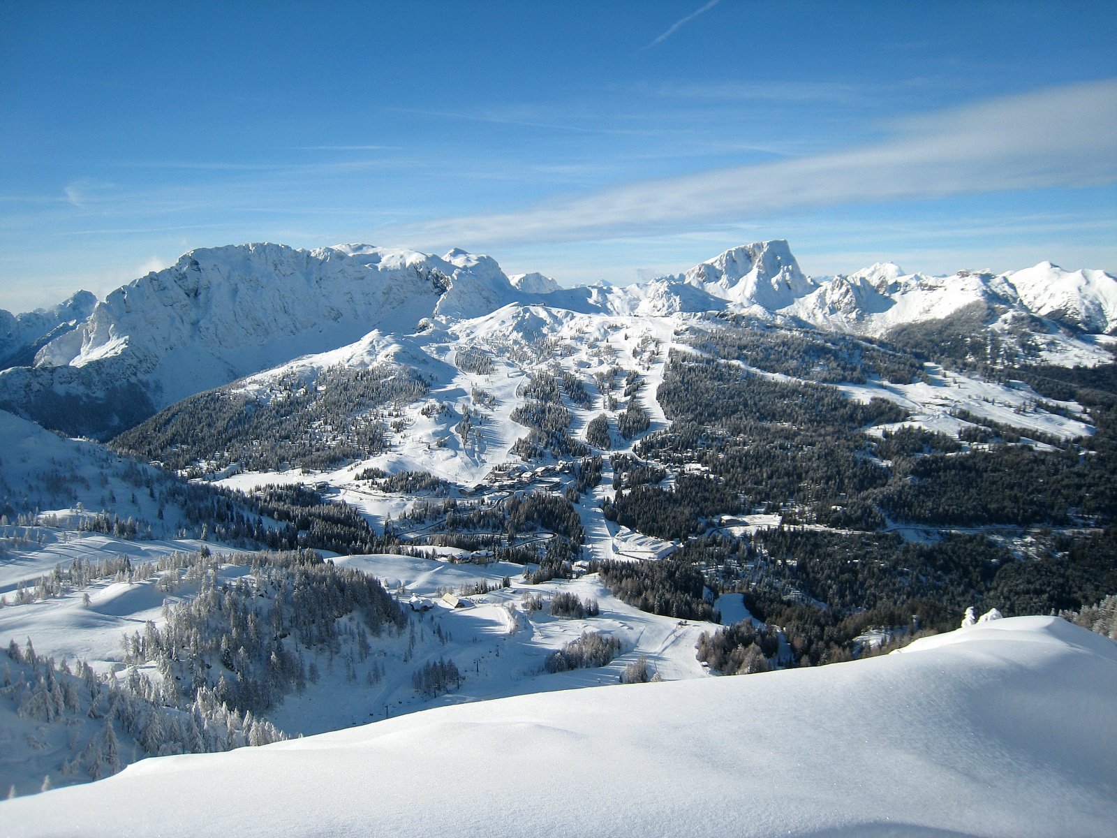 snowy mountain range with trees and hills behind