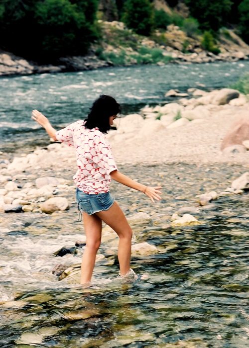 a  standing on the rocks next to a river