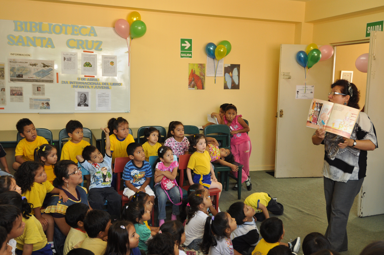 two children in yellow shirts read from a book