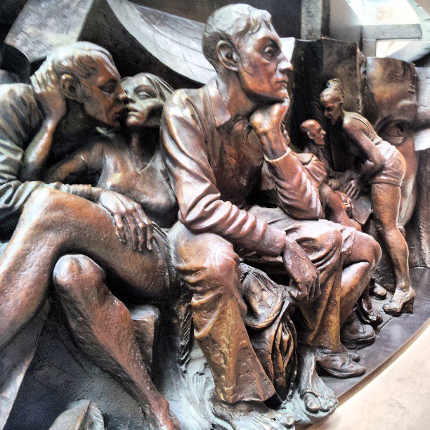 a statue of two men and a woman with their hands together