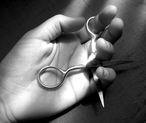 a black and white po of a person holding out their hand with a pair of scissors