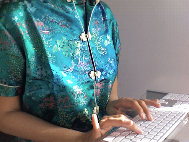 woman in turquoise top typing on a computer keyboard
