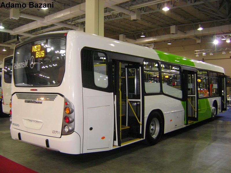 a white bus with green accents at an auto show