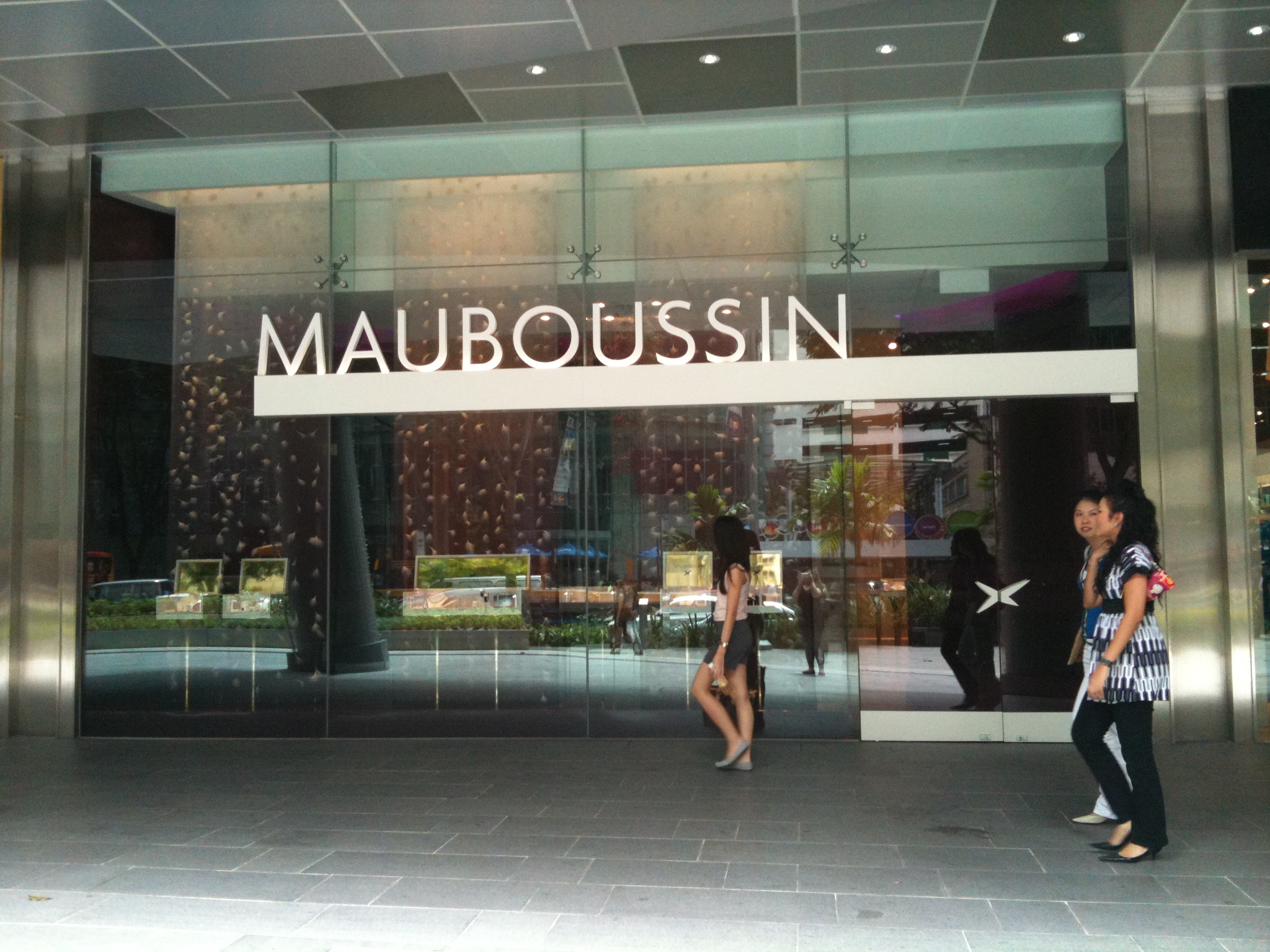 people walk in front of a store called maubousin