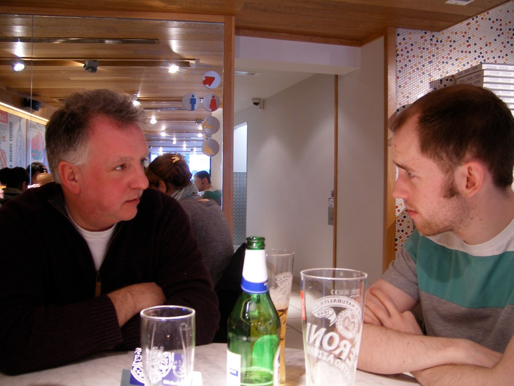 two men are sitting down at a table with drinks