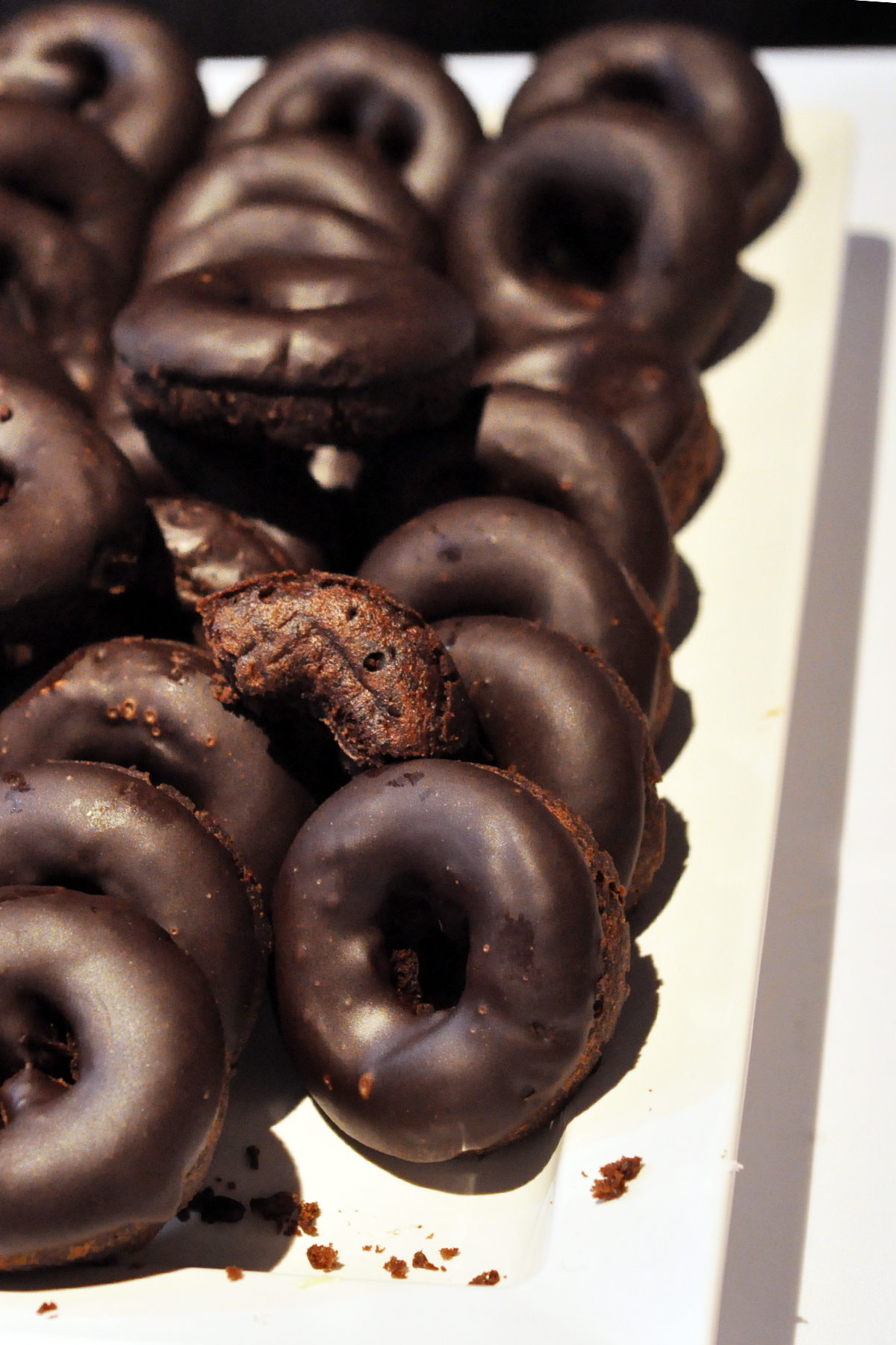 several chocolate donuts are on a plate