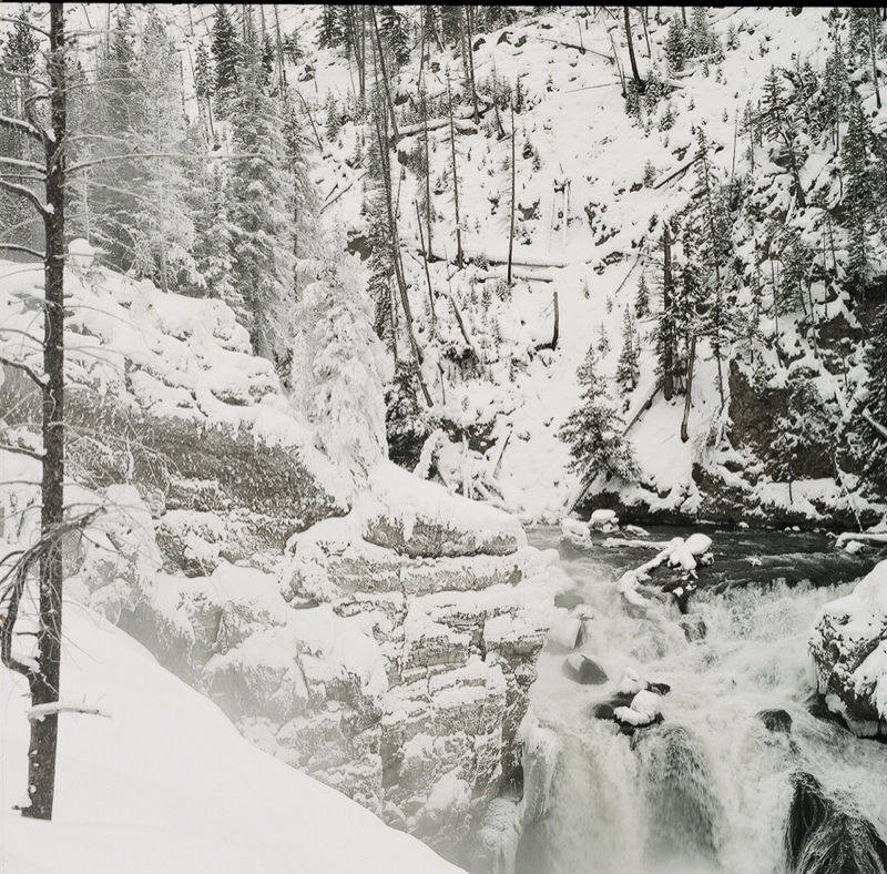 a waterfall in the middle of a snow covered forest