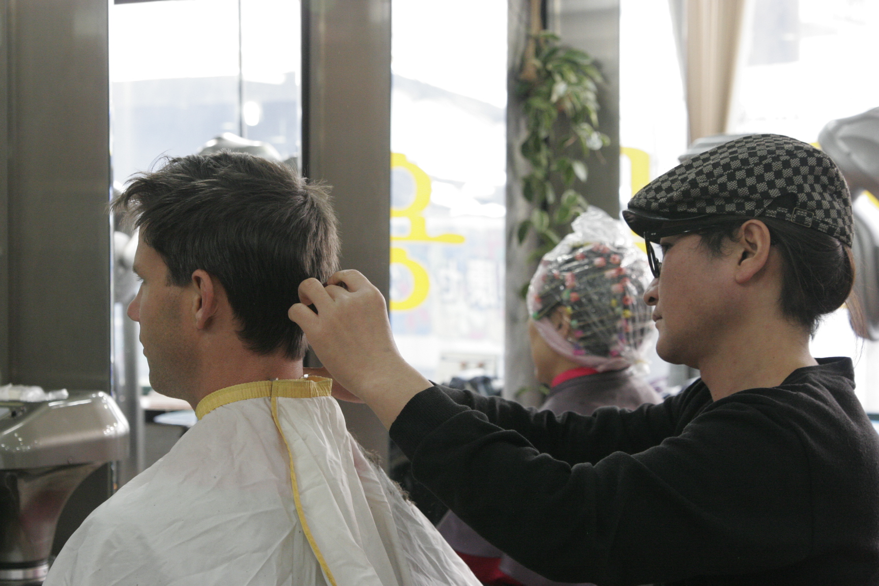 a man getting his hair done while standing in a barber shop
