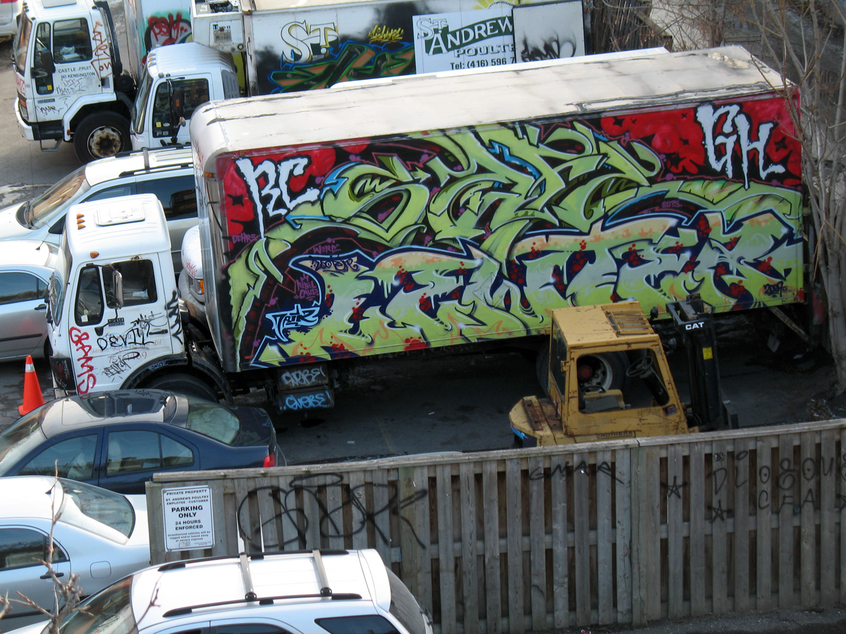 many cars and trucks all parked in a lot with some graffiti on it