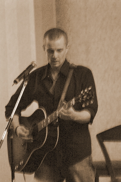 a man is holding a guitar and singing