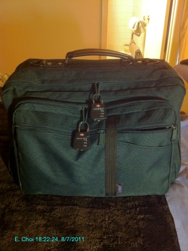 a green travel bag sitting on top of a bed