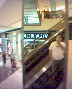a man walking down an escalator holding a drink