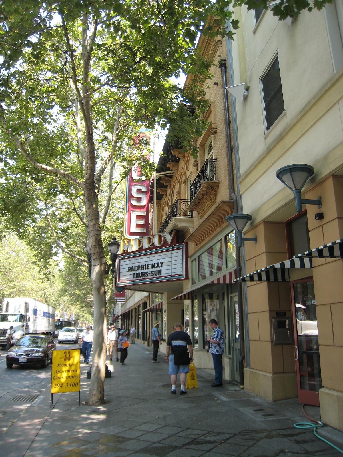 a street is lined with shops, a theater and cars