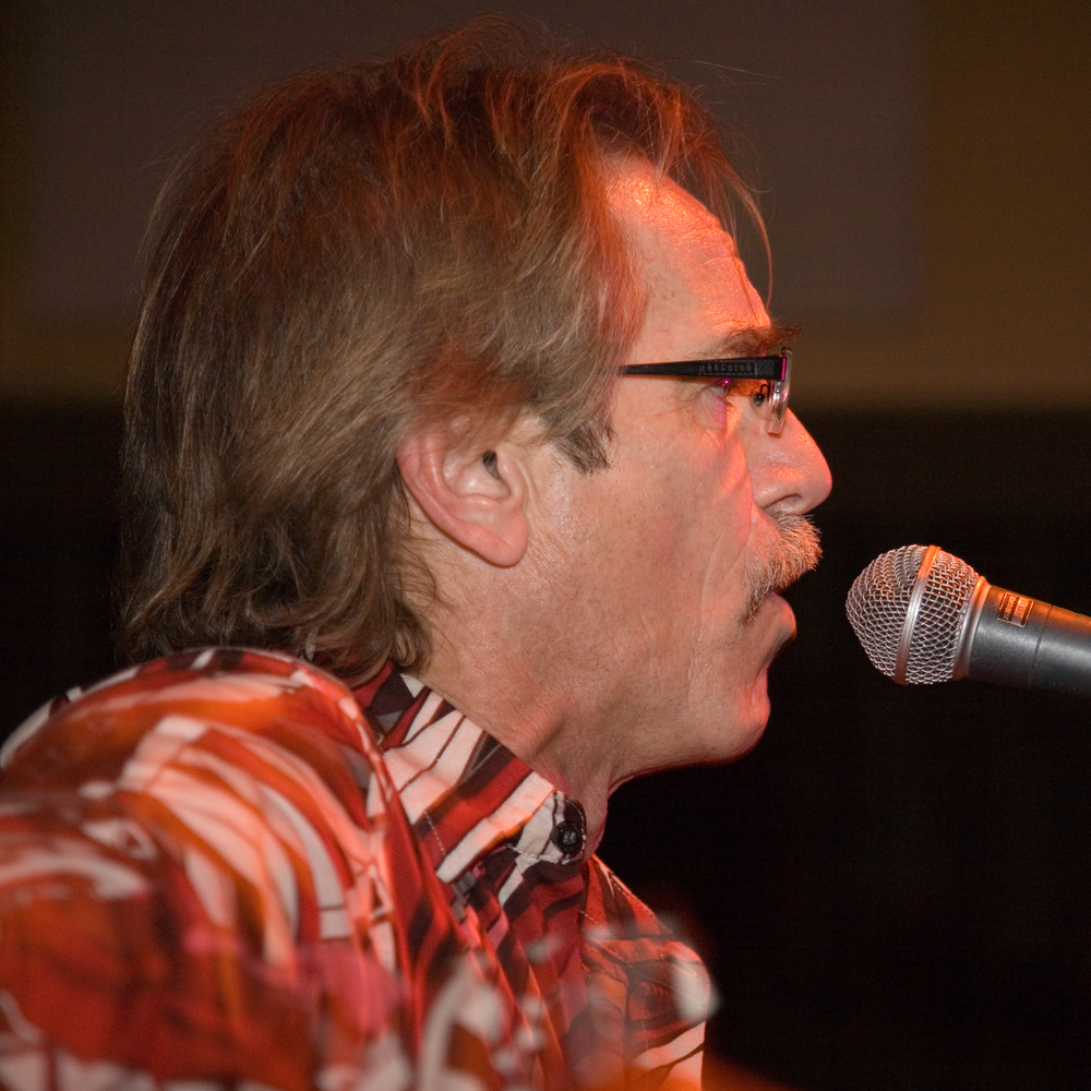 a man singing into a microphone while wearing sunglasses