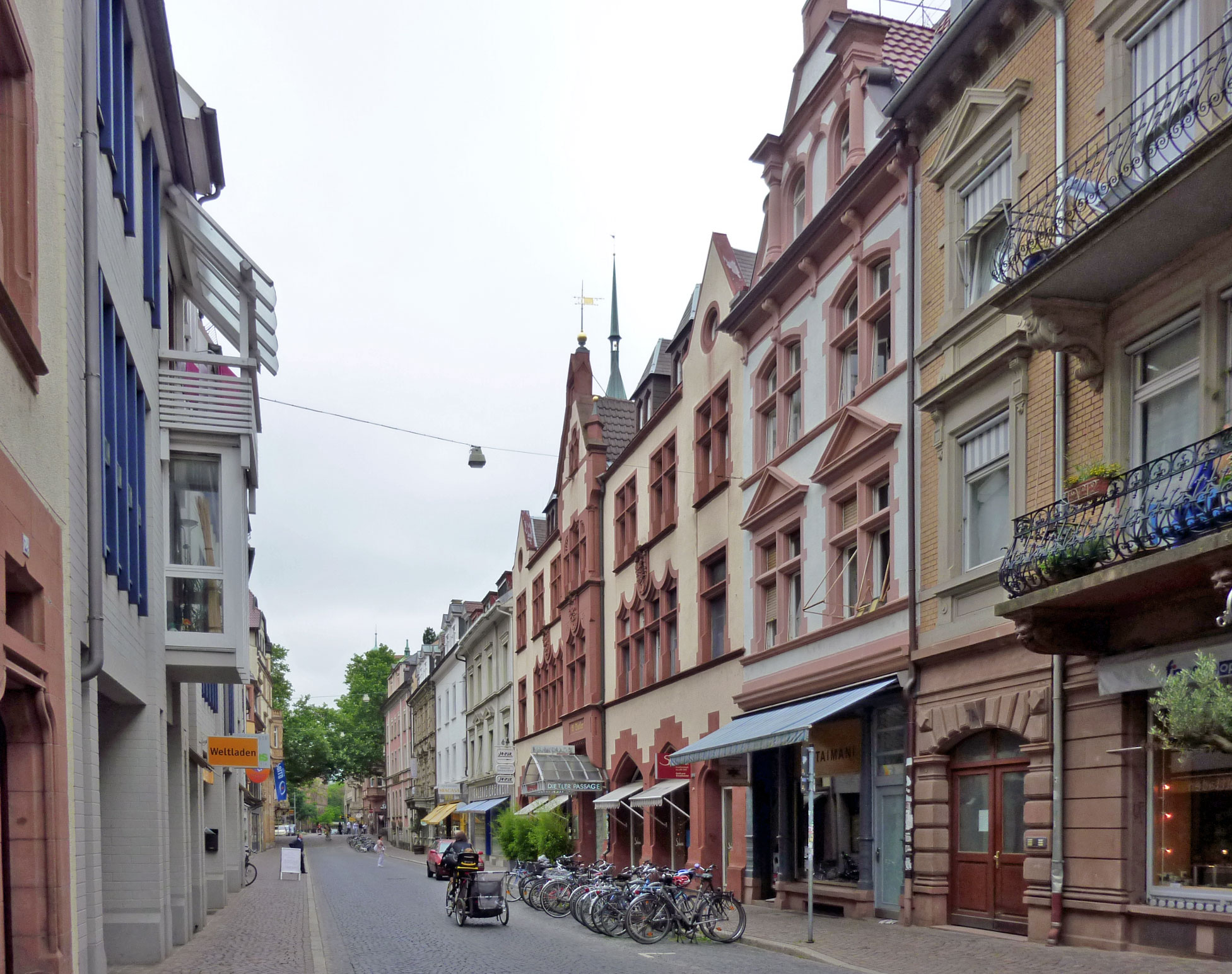 the view of several buildings, including many bicycles, is looking down a street in a european town