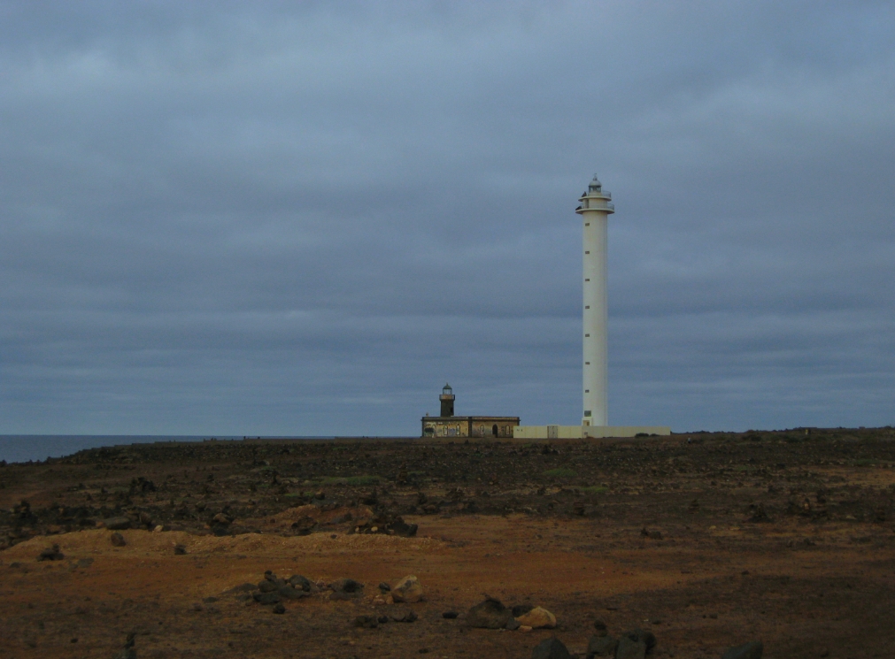 a lighthouse on top of a field under cloudy skies