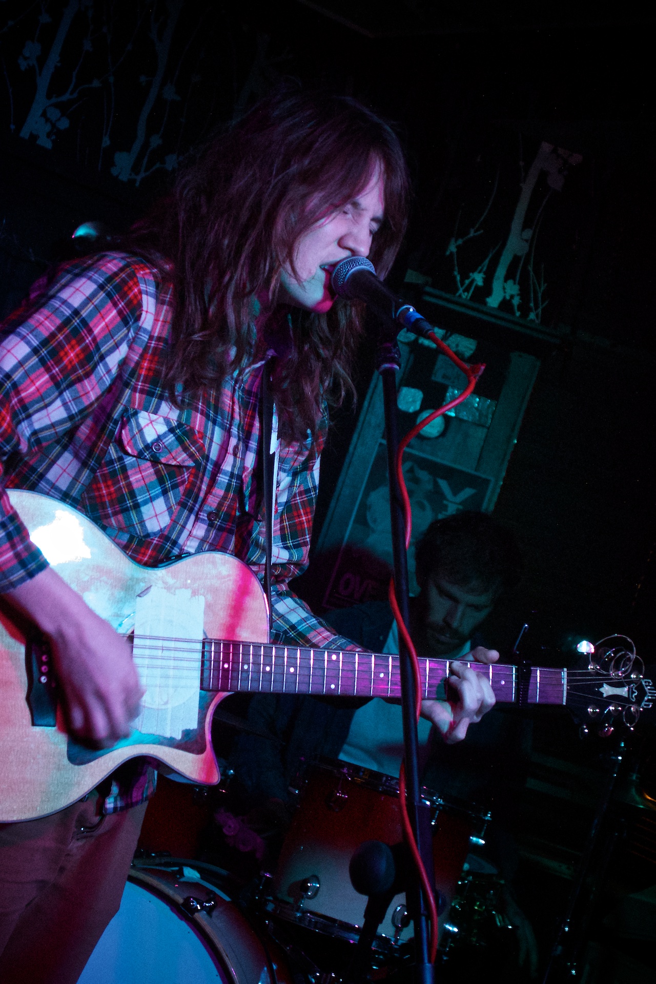 a woman singing with her guitar in front of her on stage