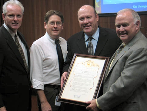 three men pose with an award on a stage