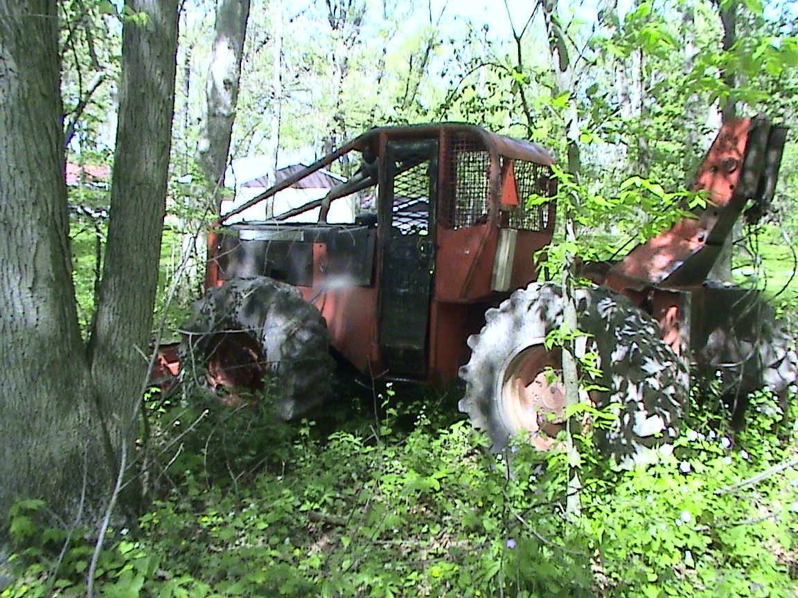 an old rusty tractor sitting in the forest