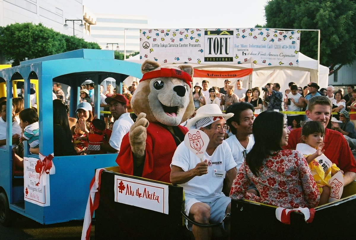 a mascot waving and riding in a float with people