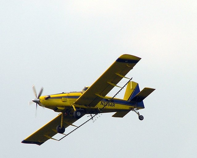 a small yellow airplane with propellers flying in the sky