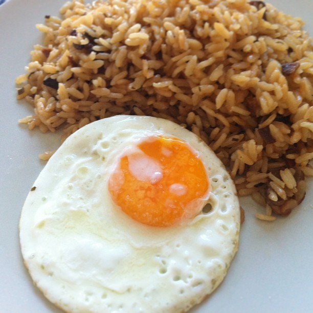 a fried egg on top of rice next to a fork