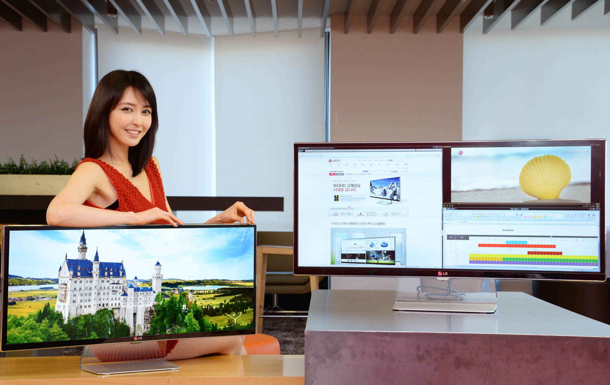 a woman holds up a large painting behind her computer monitor