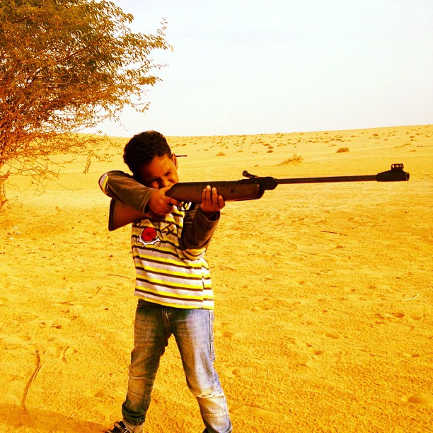 a little boy is holding an empty rifle