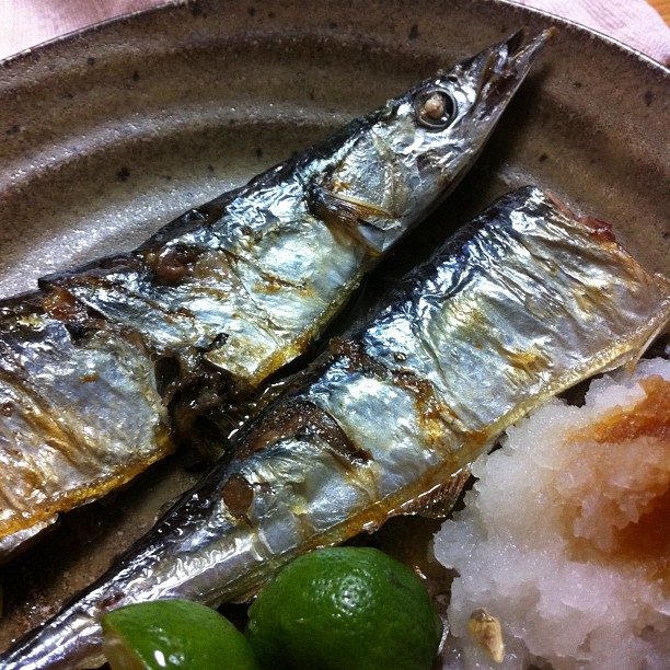 two fish are sitting on a plate with salt and limes