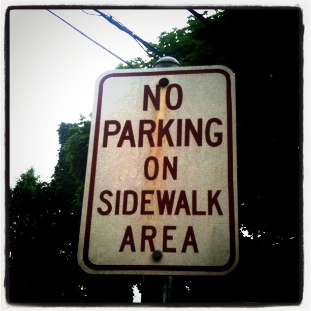 a sign in a city street that says no parking on sidewalks