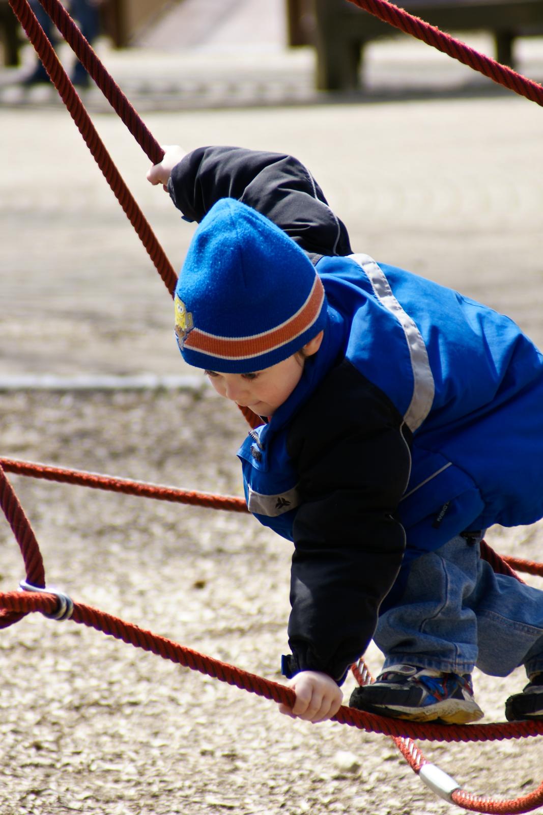 the little boy is playing on a metal rope