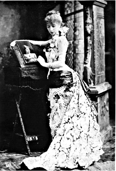 black and white pograph of a woman in a long dress leaning against a piano