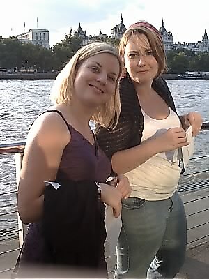 two women standing on a dock with a city skyline in the background