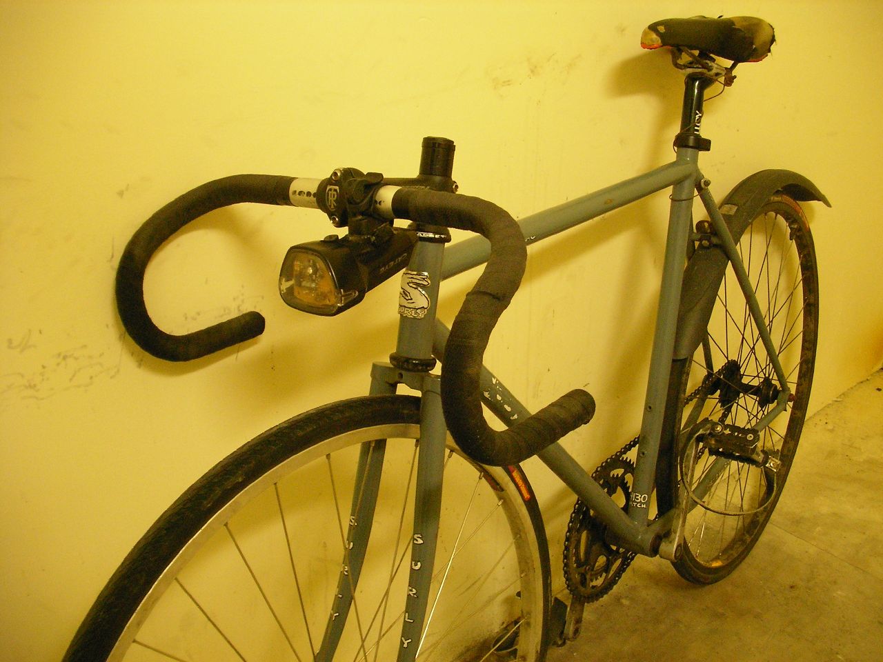 a bicycle locked to the side of a yellow wall