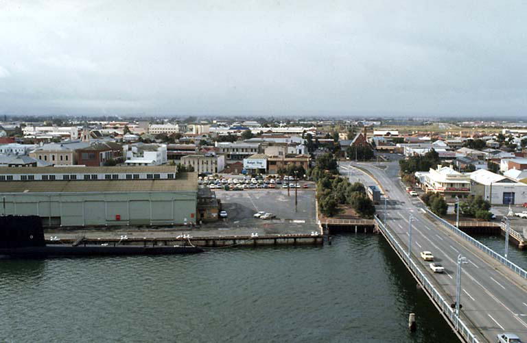a wide street and parking lot is along the edge of the water