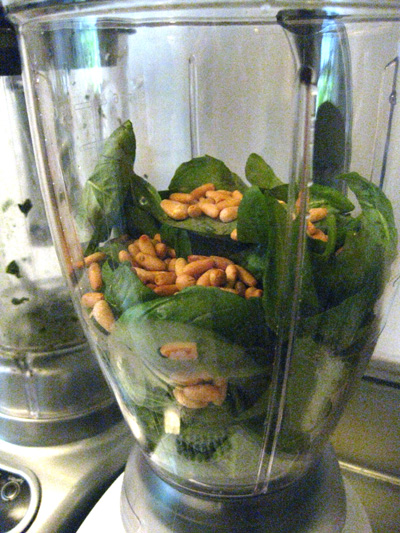 green vegetables and nuts are in a food processor