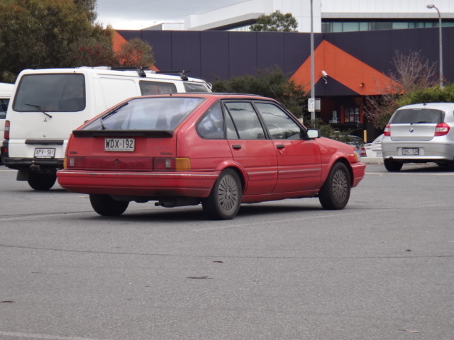 an older red car is parked in a parking lot