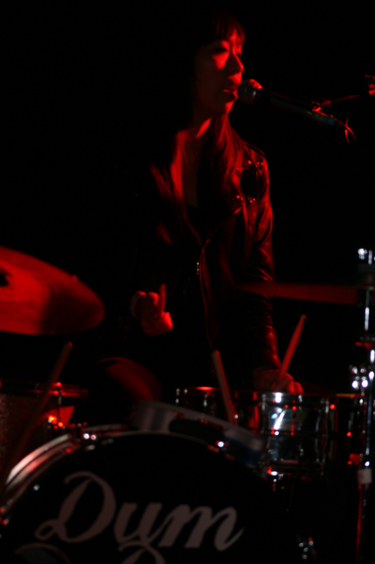 a young man standing next to a drum set on stage