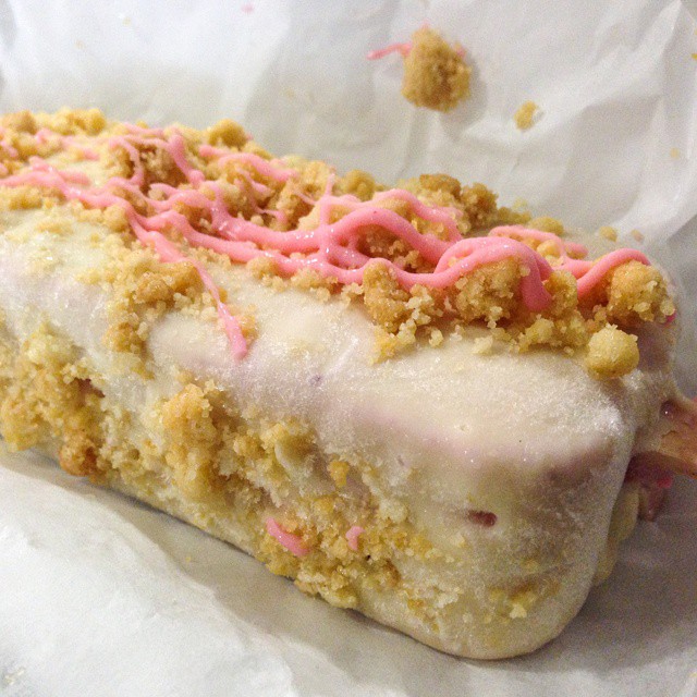 a cake roll on wax paper is decorated with pink and white icing