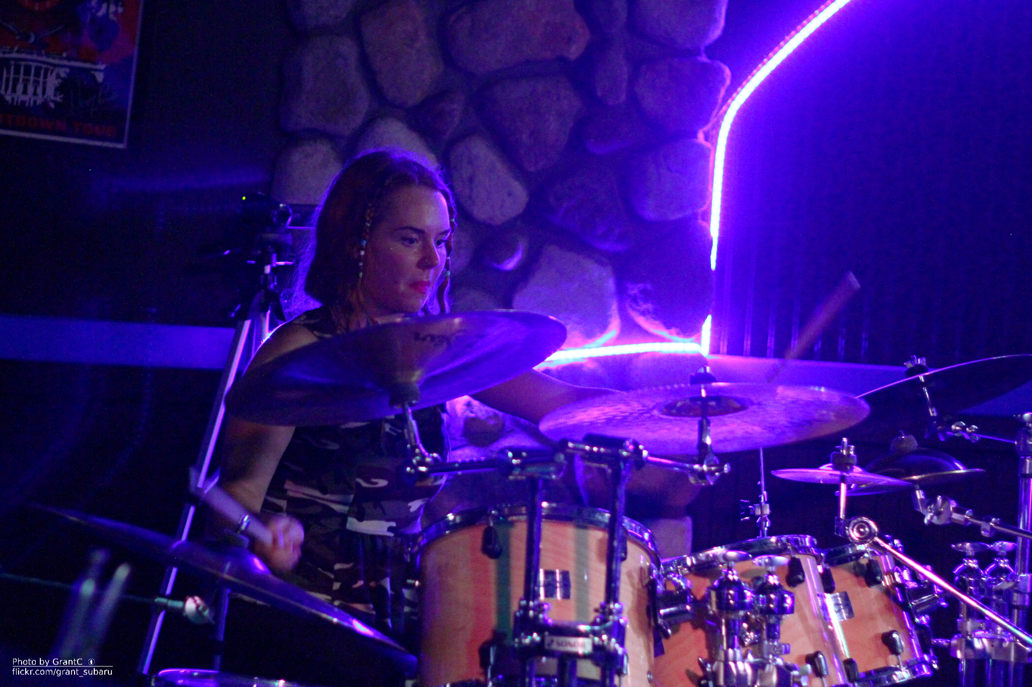 a girl plays drums in front of purple lights