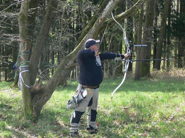 an older man is standing on the ground aiming at soing