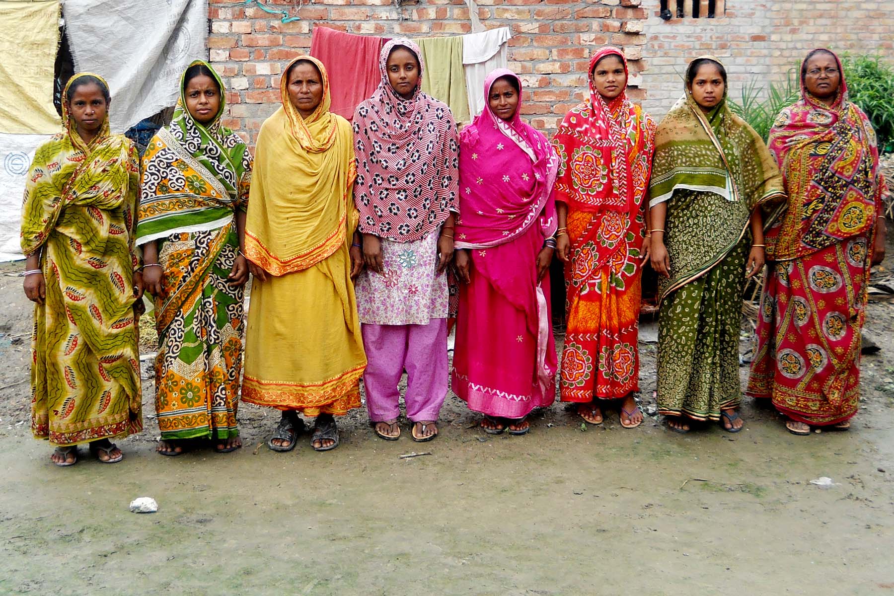 six women are standing in front of a brick wall