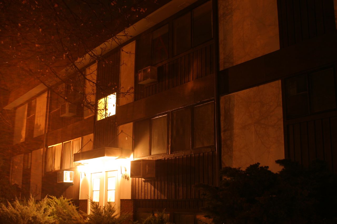the view of a building in the dark, showing windows and doors