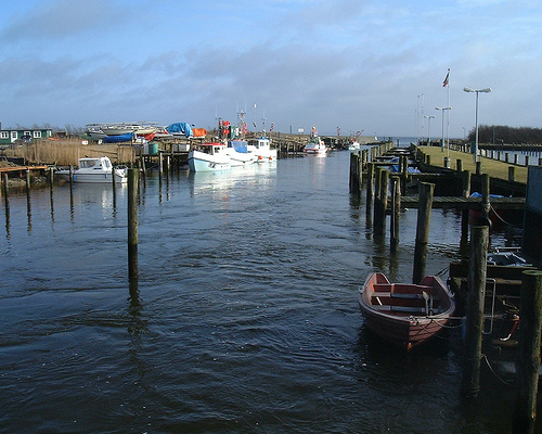 a wooden dock with several boats and one is floating in the water